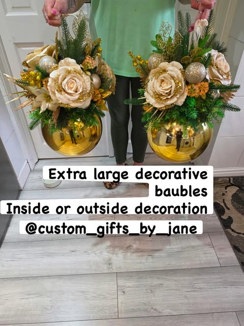 Two gold decorative baubles filled with cream roses and gold foliage